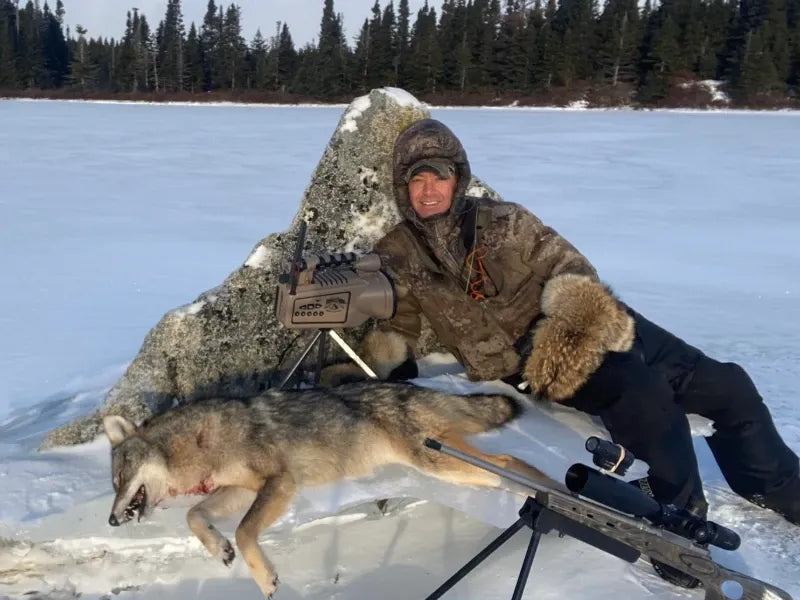 Hunter with a wolf on a frozen lake, using the GardePro X66 Pro cellular trail camera to track nocturnal predators