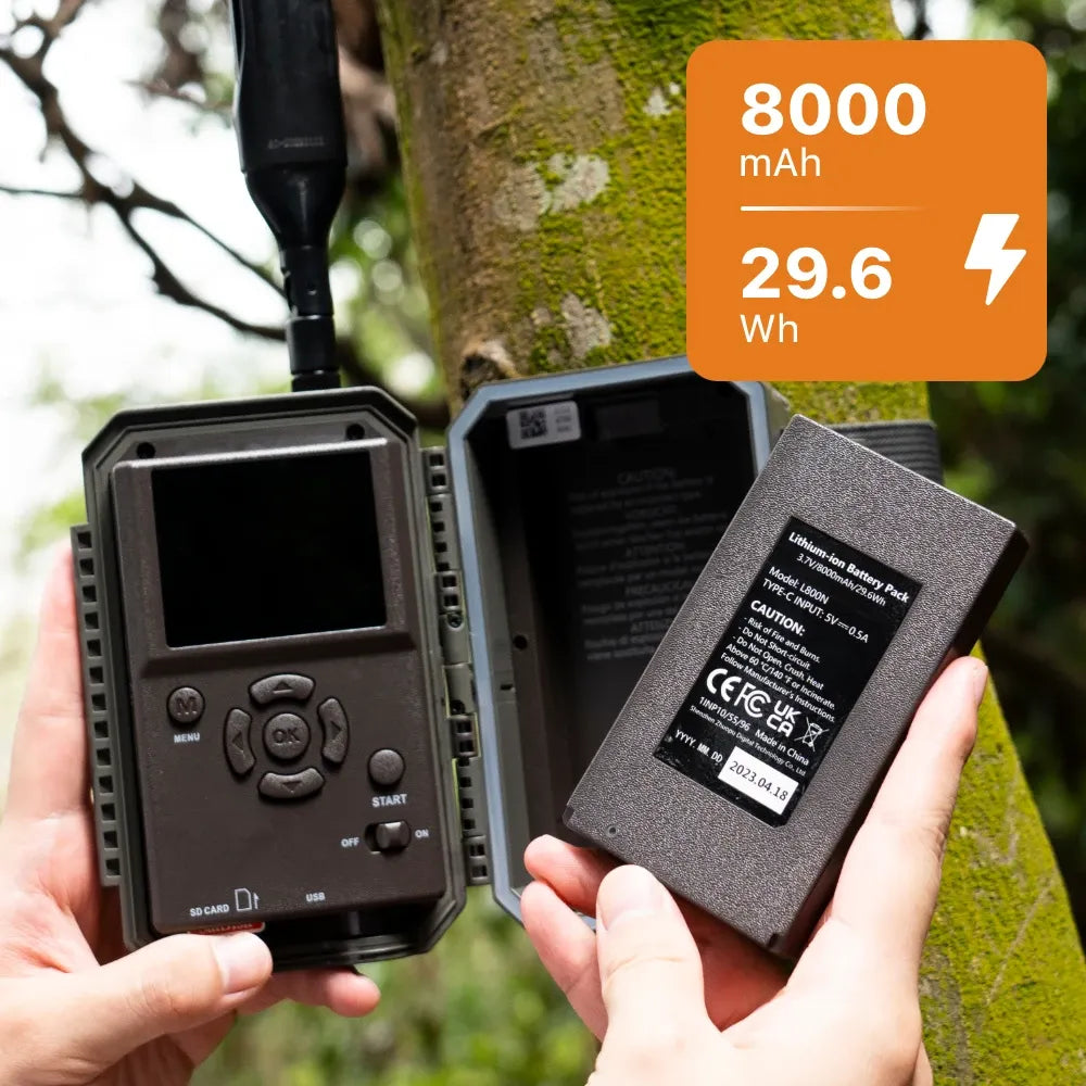 Hands installing an 8000mAh lithium-ion battery pack into a cellular trail camera.
